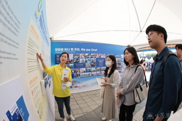 3. 25일 서울 올림픽 평화의 광장에 마련된 IWPG 홍보부스에서 직원이 시민에게 설명하고 있다..JPG